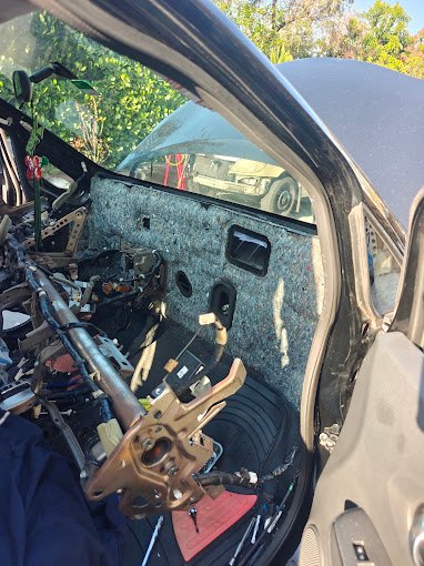 Car interior with the entire dashboard removed, exposing the steering column and firewall insulation for an evaporator replacement